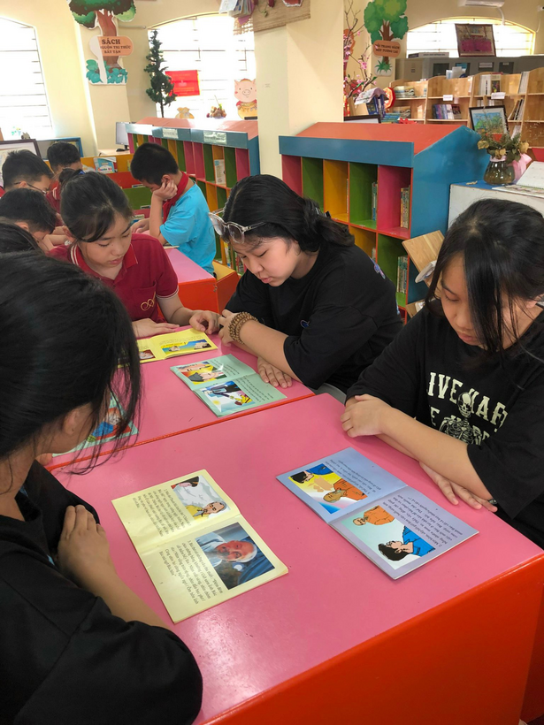 A group of people sitting at a table looking at books
Description automatically generated with low confidence