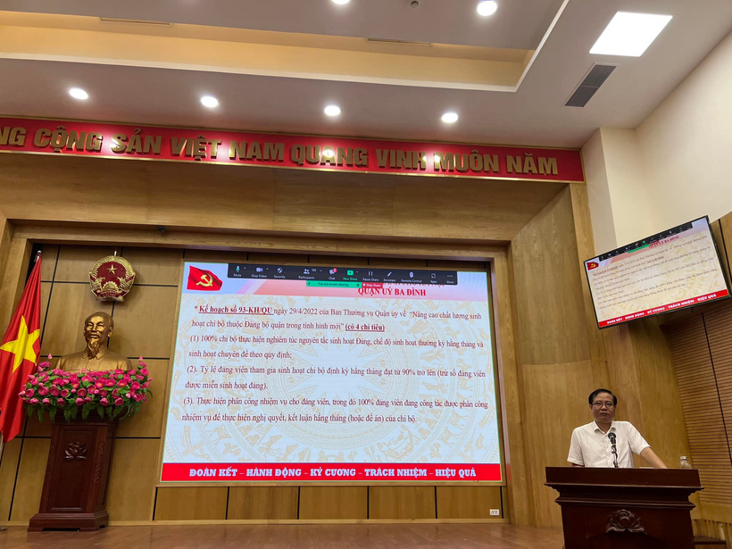 A person sitting at a podium in front of a large screen
Description automatically generated with low confidence