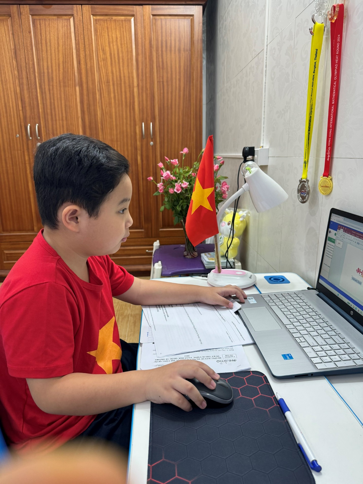 A child sitting at a desk using a computer
Description automatically generated