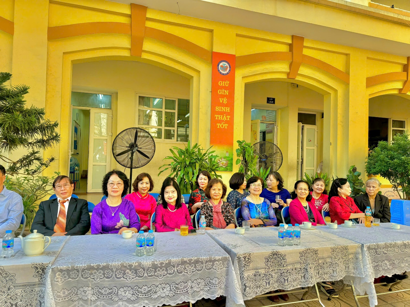 A group of people sitting at tables outside a building

Description automatically generated