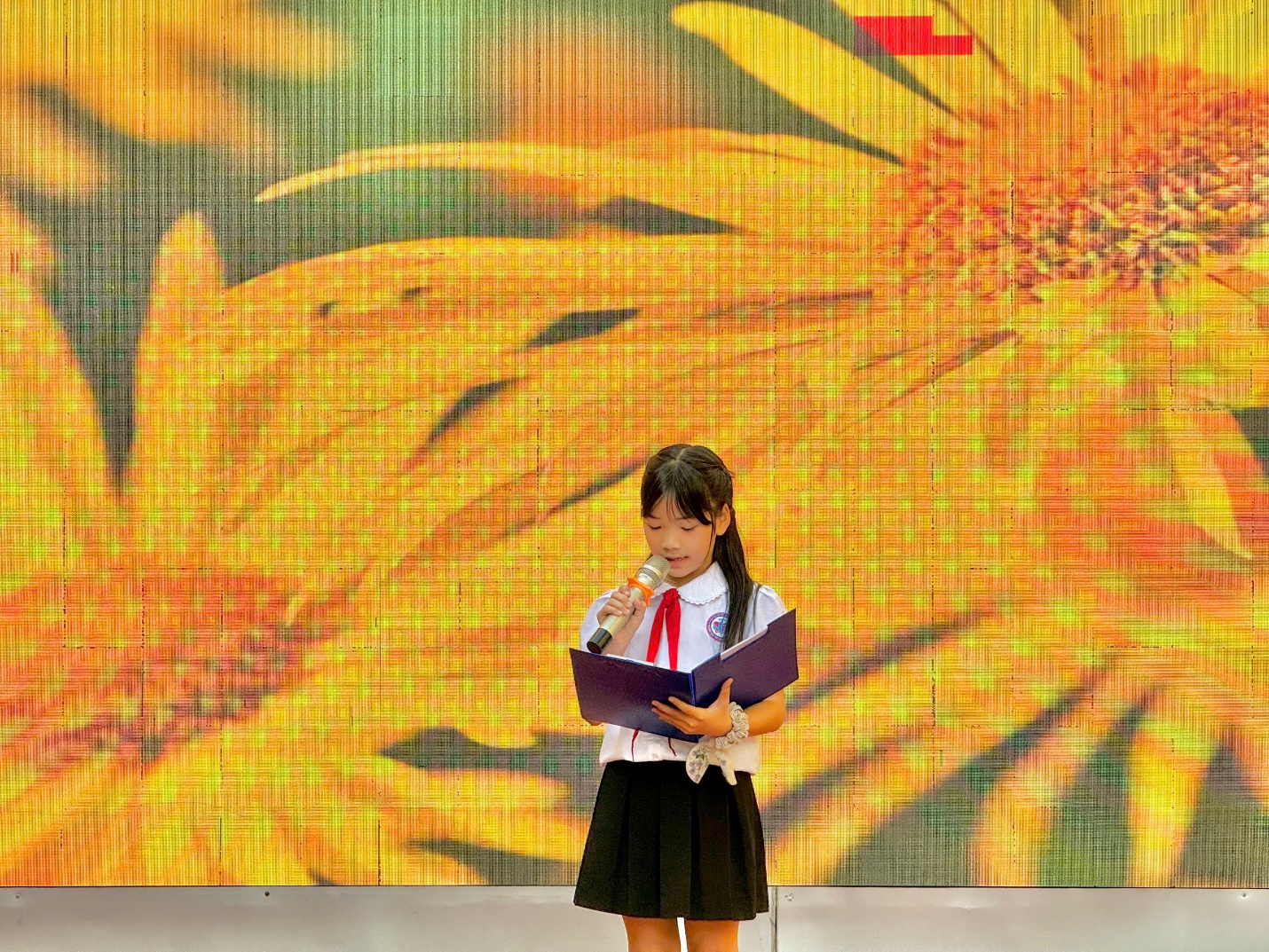 A child holding a microphone and speaking into a book

Description automatically generated