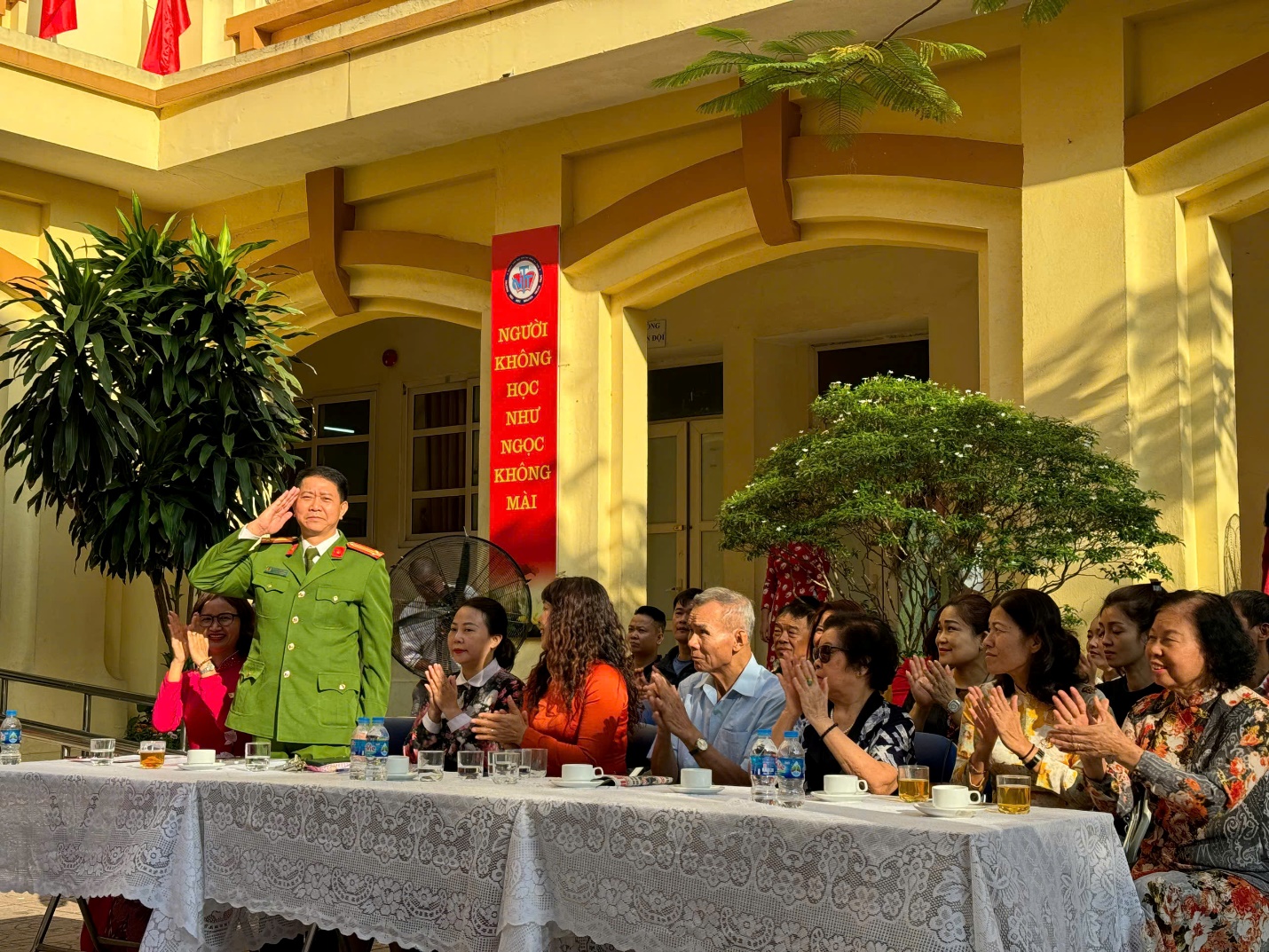 A group of people sitting at a table with a person saluting

Description automatically generated