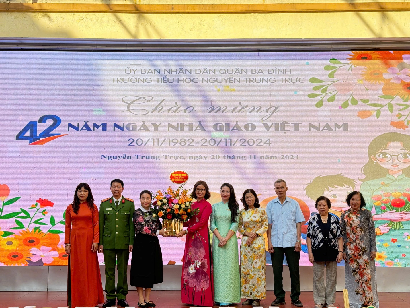 A group of people standing in front of a large screen

Description automatically generated