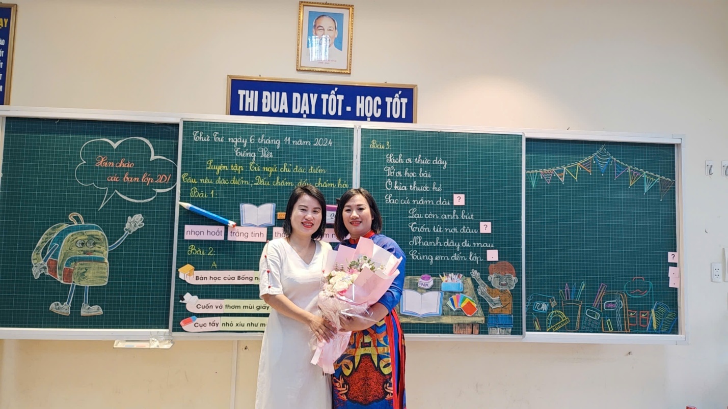 Two women standing in front of a chalkboard
Description automatically generated
