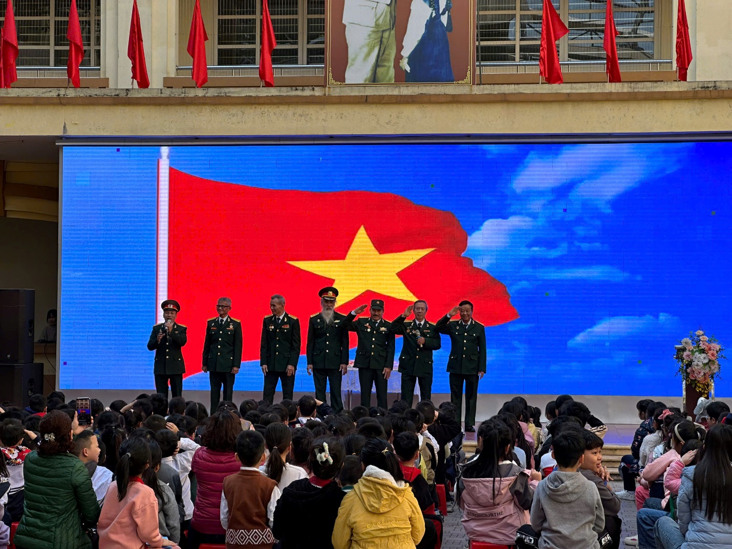 A group of people in uniform standing in front of a large screen
Description automatically generated