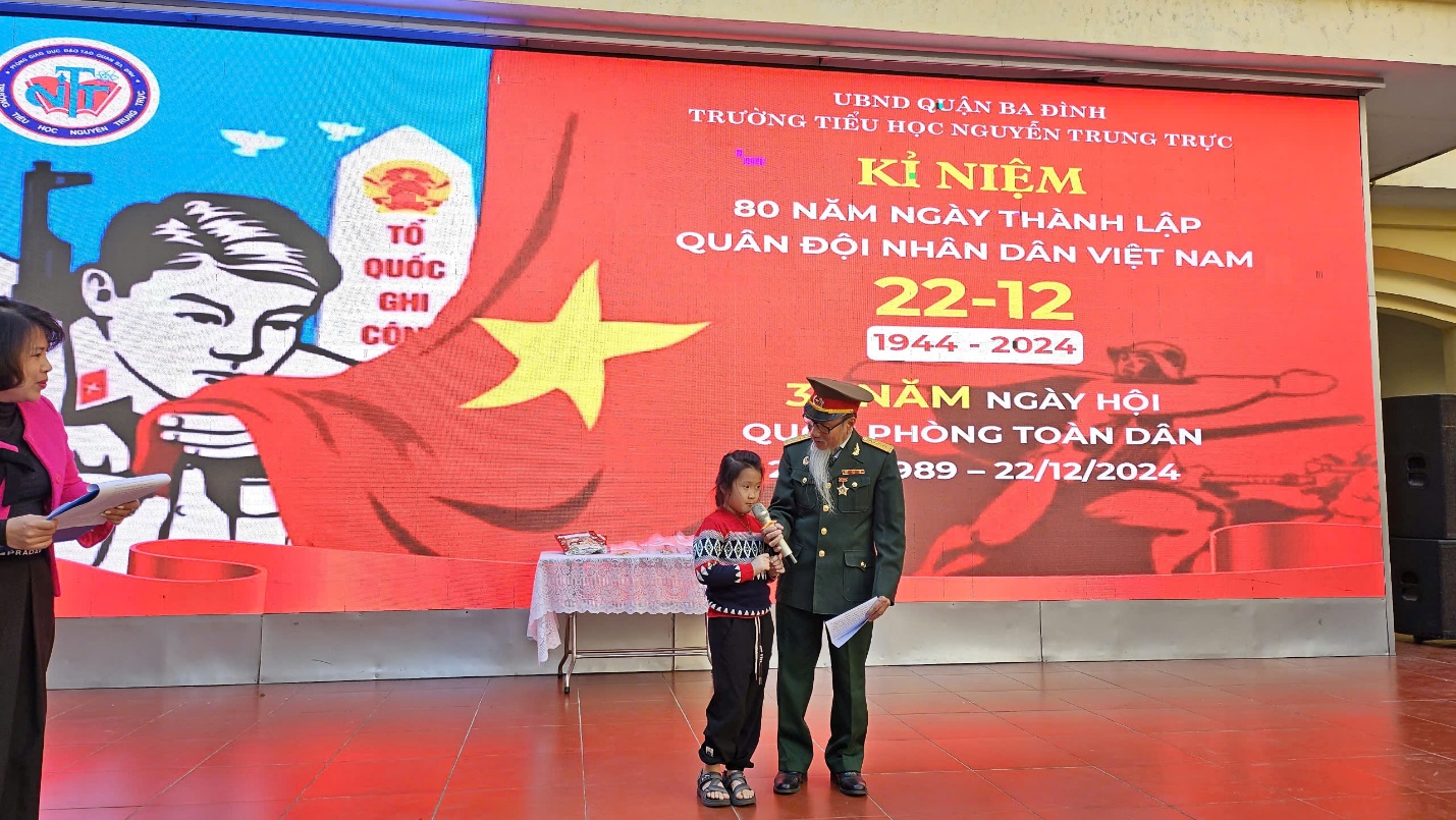 A person and a child standing in front of a large banner
Description automatically generated