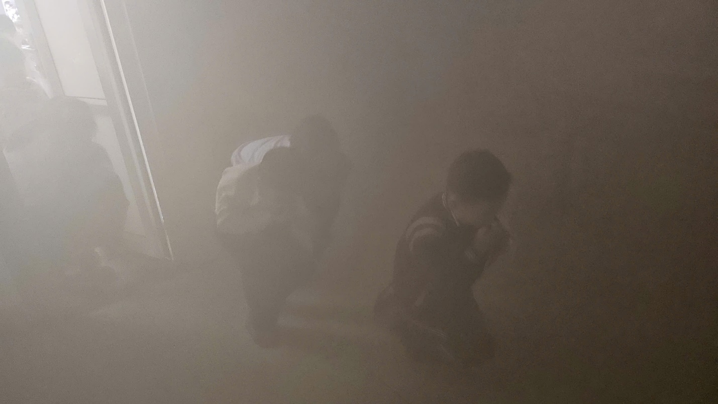 Two people kneeling down in a foggy room

Description automatically generated