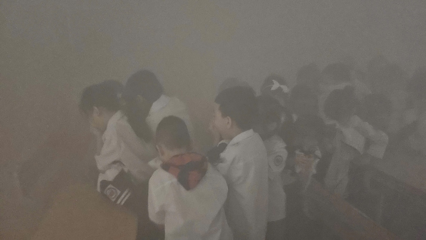 A group of people standing in a room

Description automatically generated