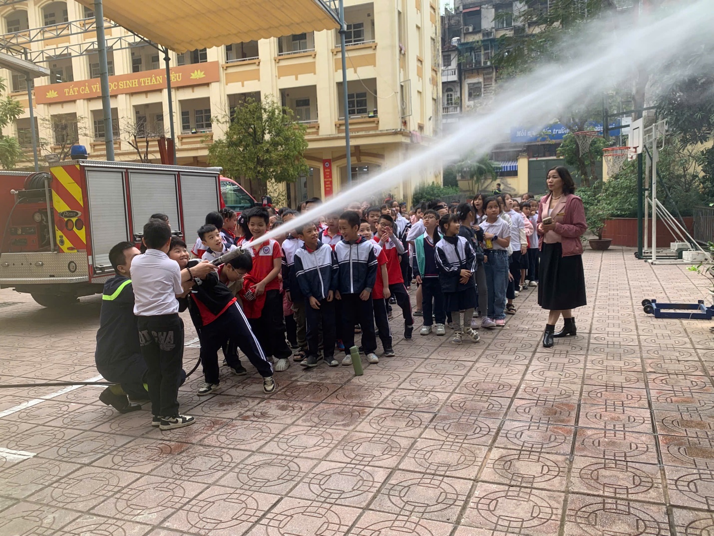 A group of children spraying water on a sidewalk

Description automatically generated