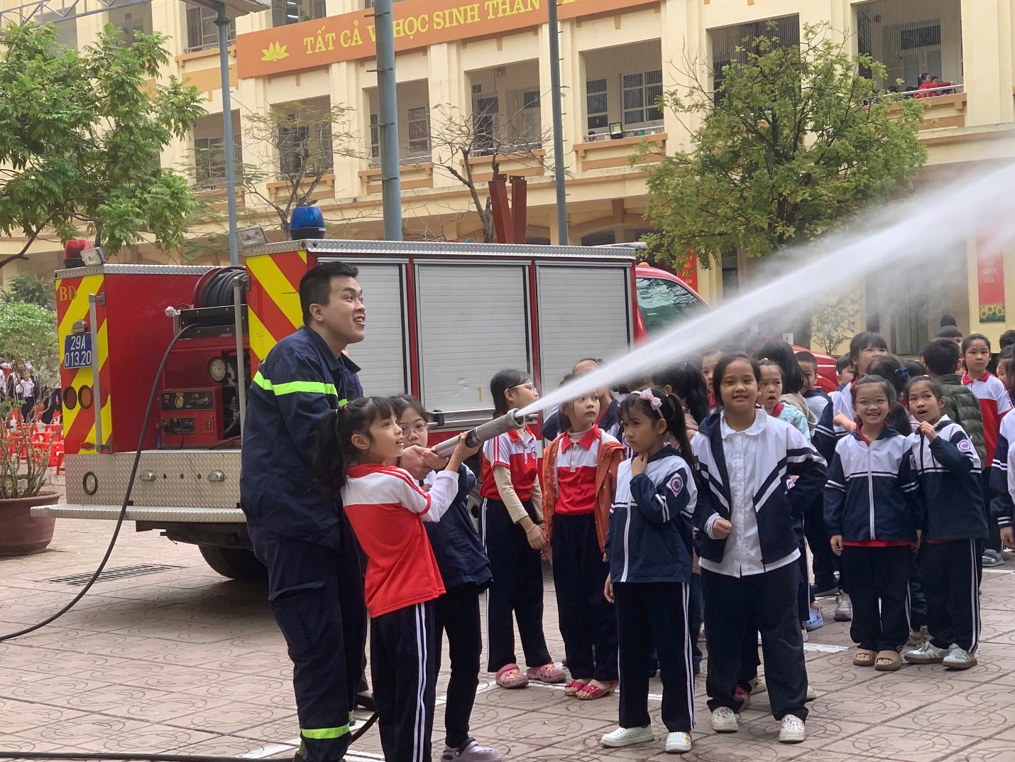 A fireman spraying water on a group of children

Description automatically generated