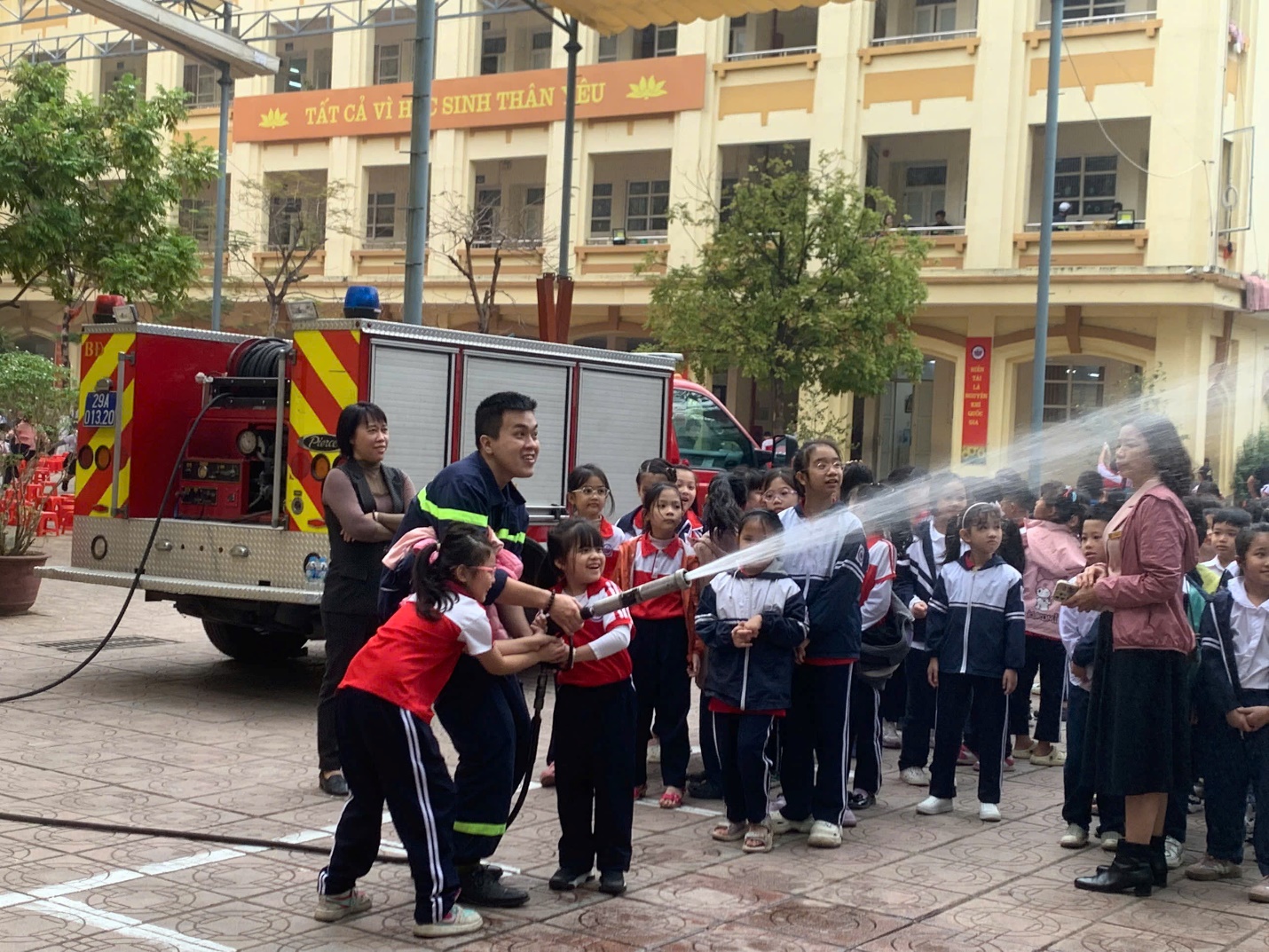 A group of children spraying water with a fire hose

Description automatically generated