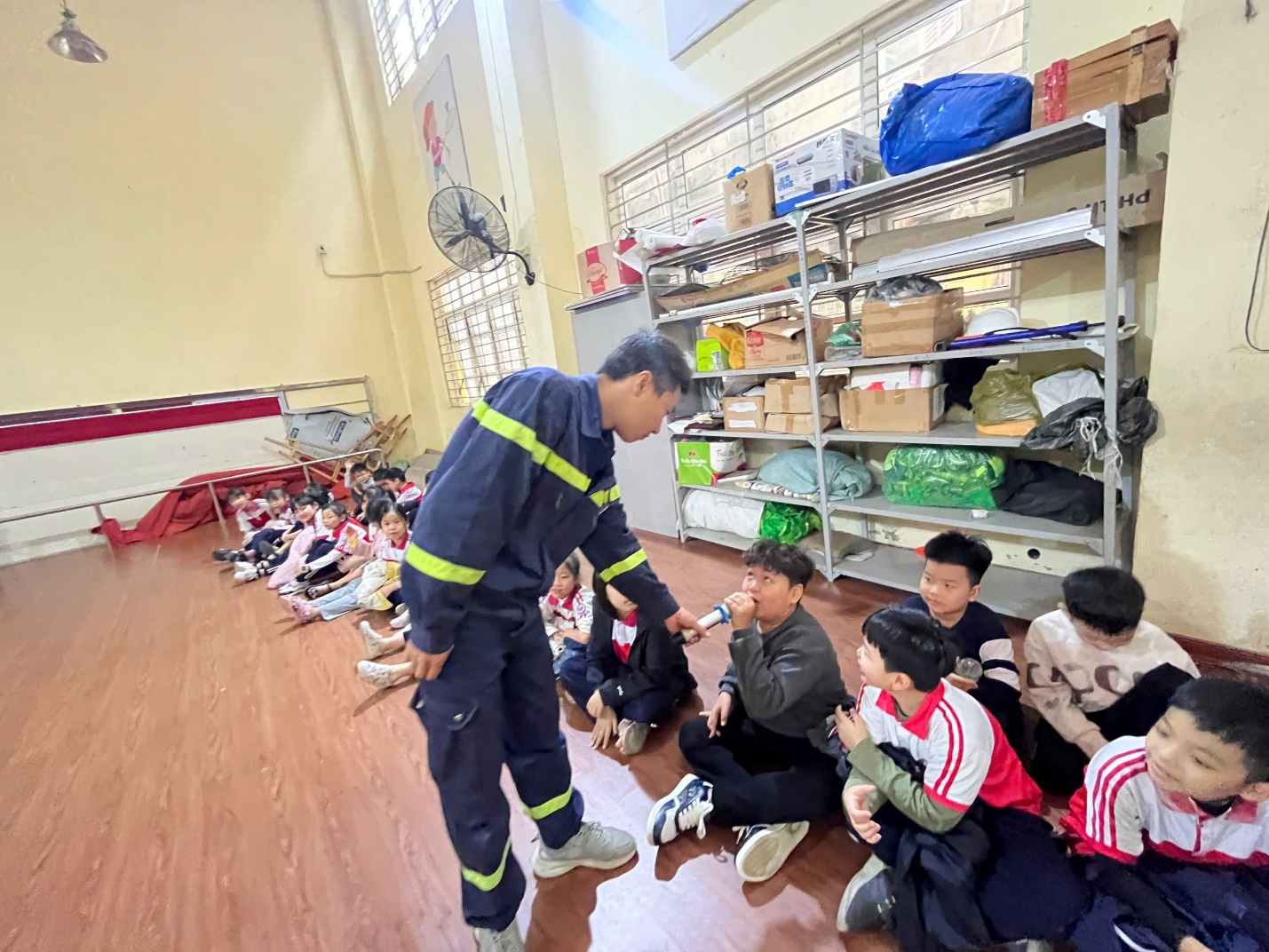 A person in a uniform standing in front of a group of kids

Description automatically generated