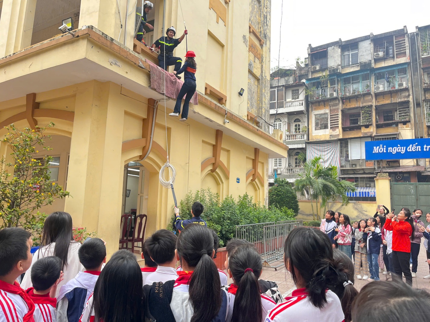 A group of people looking at a person from a building

Description automatically generated