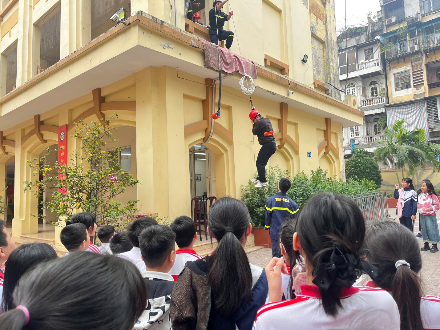 A group of people watching a person from a rope

Description automatically generated