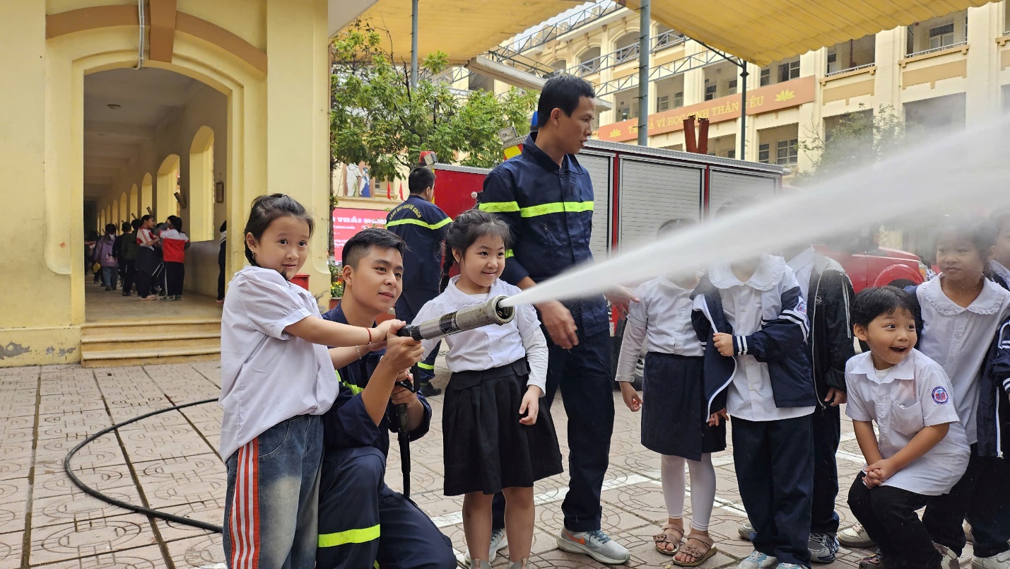 A group of children spraying water on a fire hose

Description automatically generated