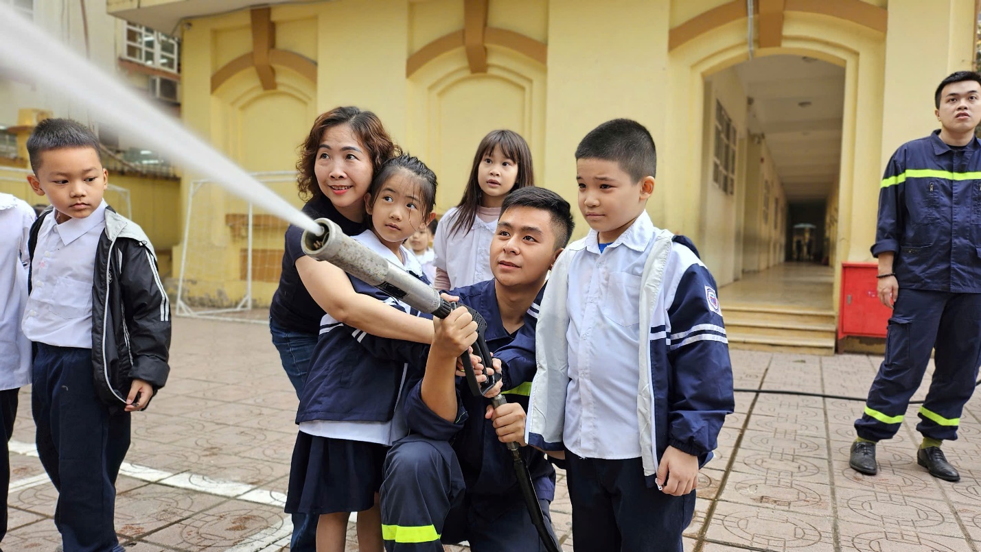 A group of children and a person holding a hose

Description automatically generated