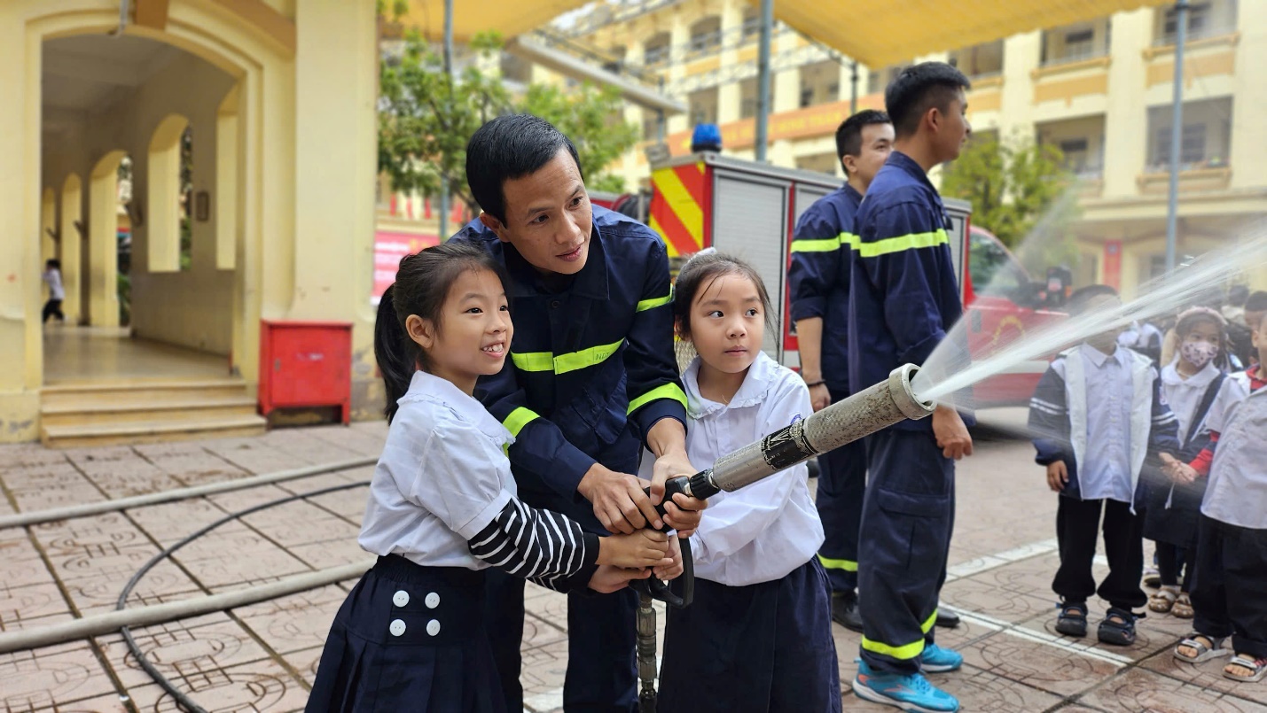 A group of children holding a fire hose

Description automatically generated