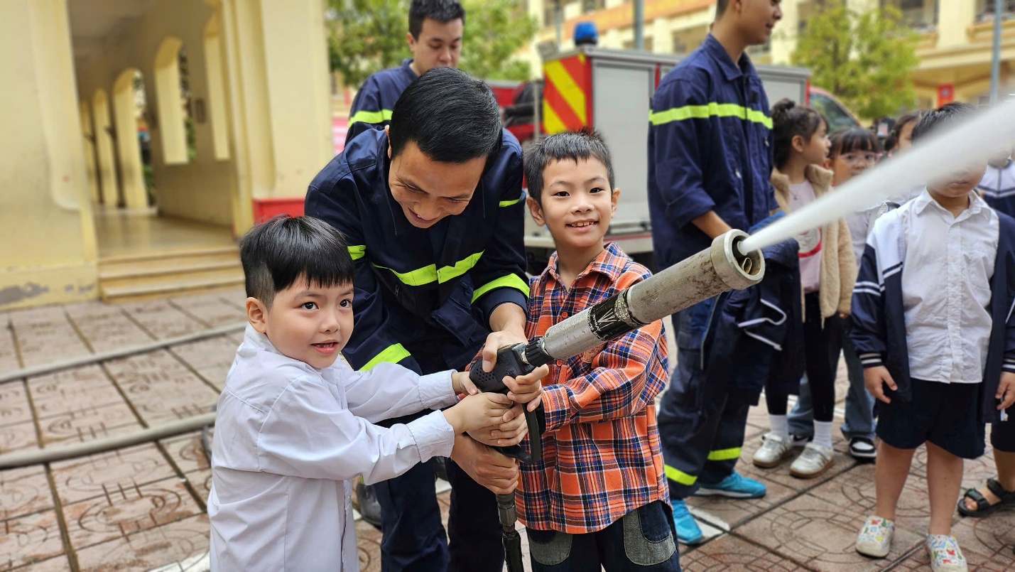 A group of people holding a hose with a fireman

Description automatically generated