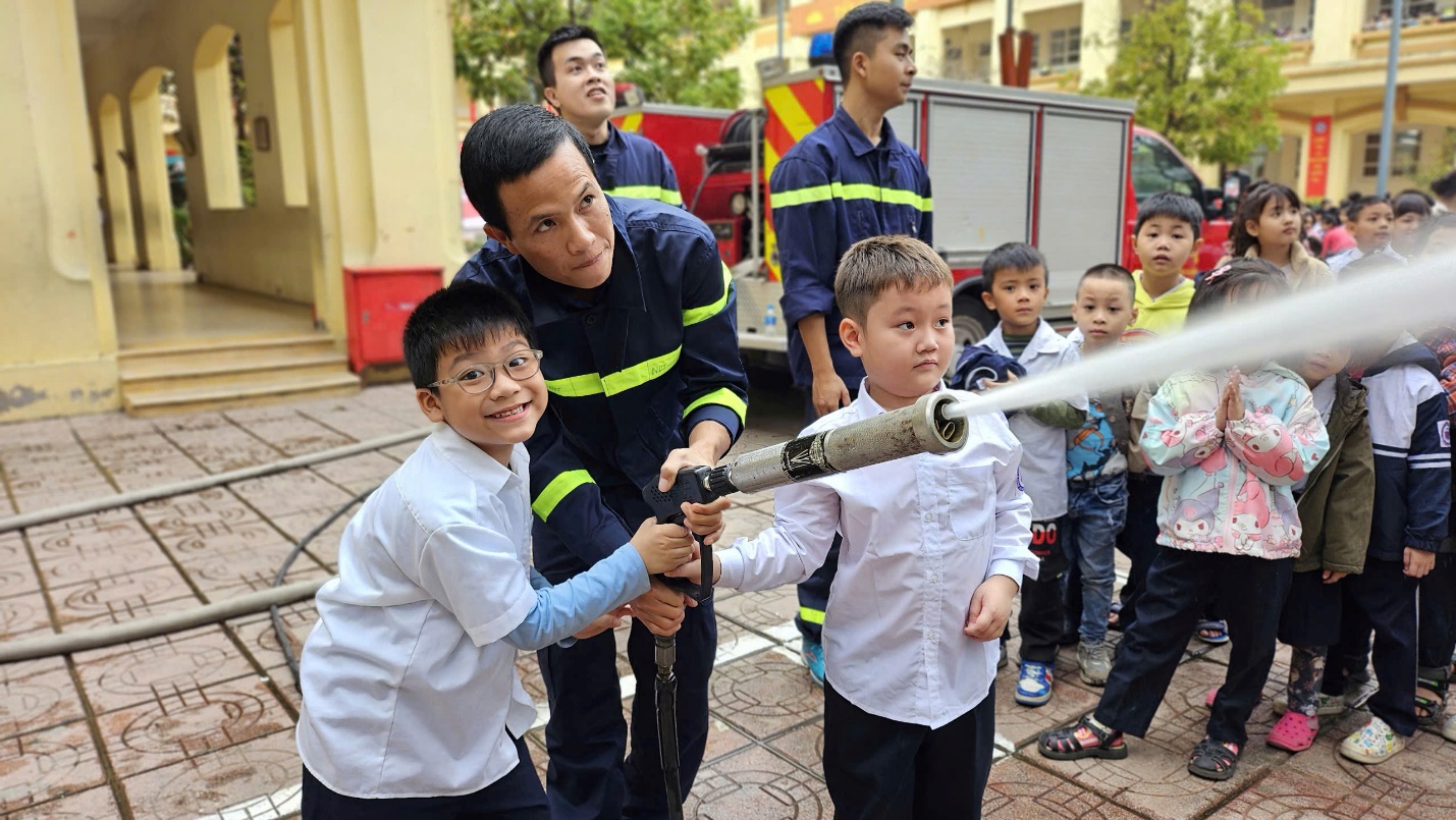 A group of children playing with a hose

Description automatically generated