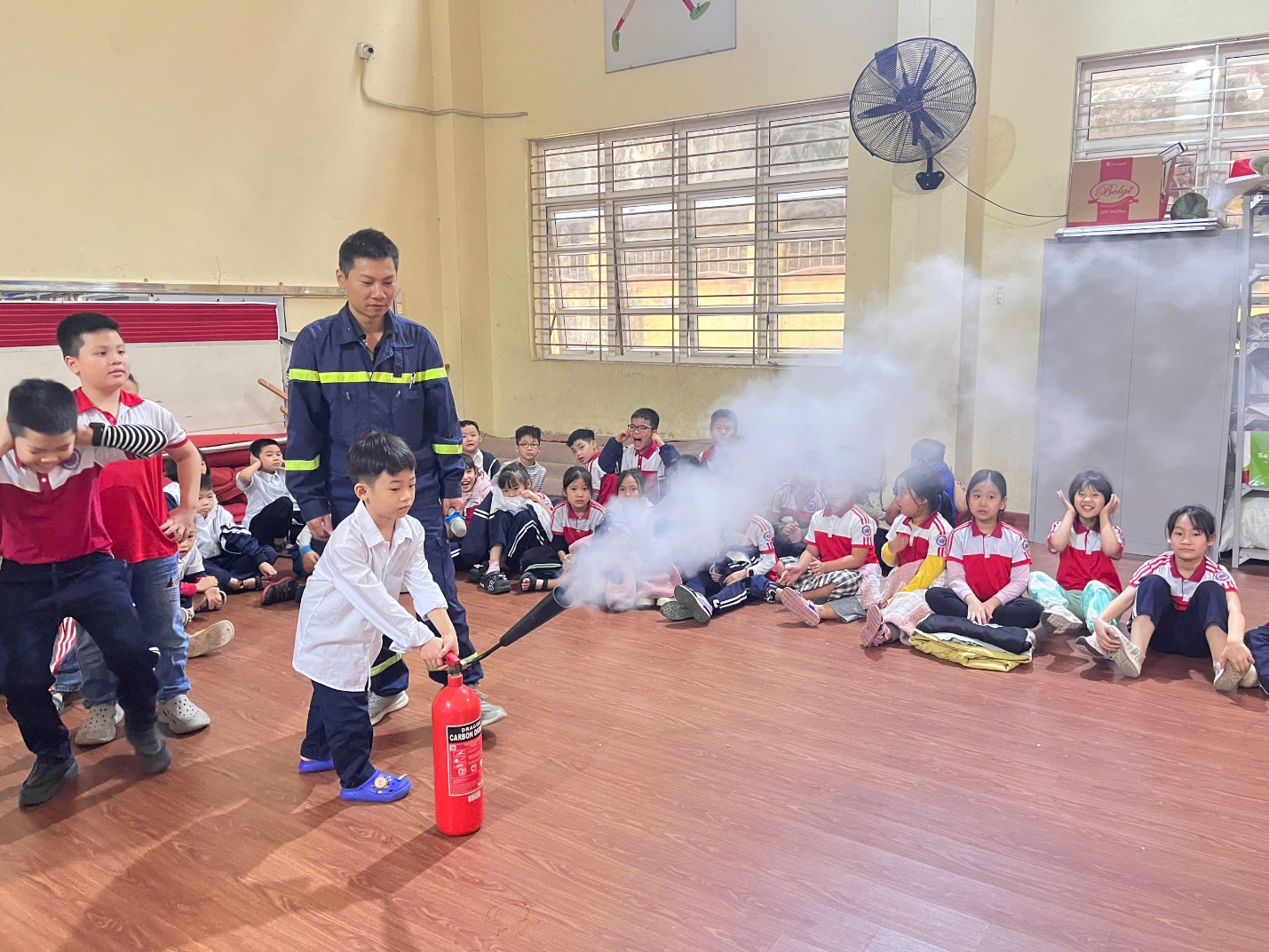 A group of children in a room with a fire extinguisher

Description automatically generated