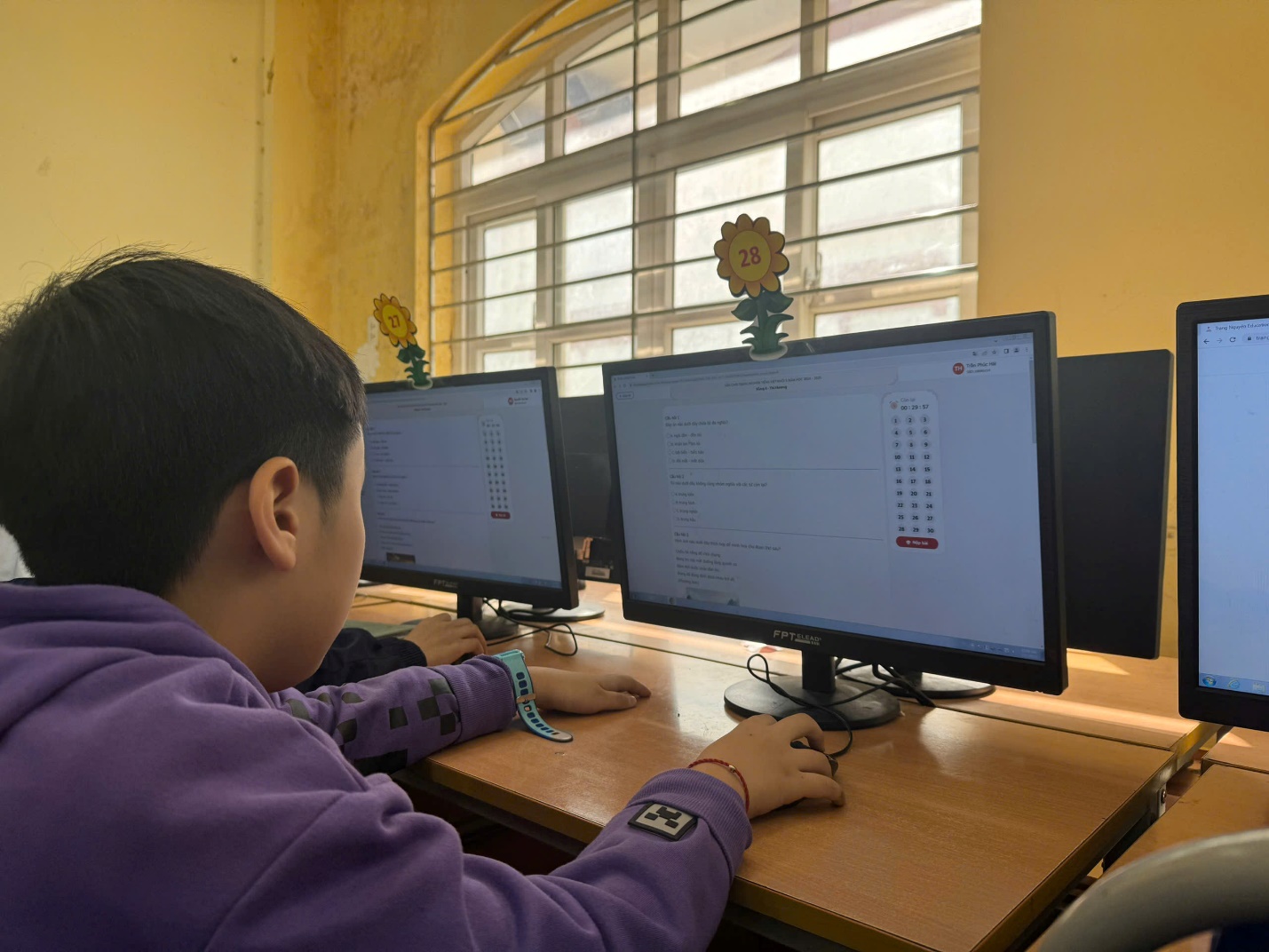 A child sitting at a desk with computers

Description automatically generated