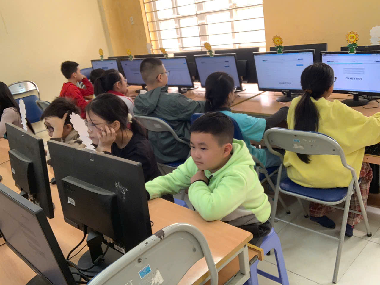 A group of children in a classroom with computers

Description automatically generated