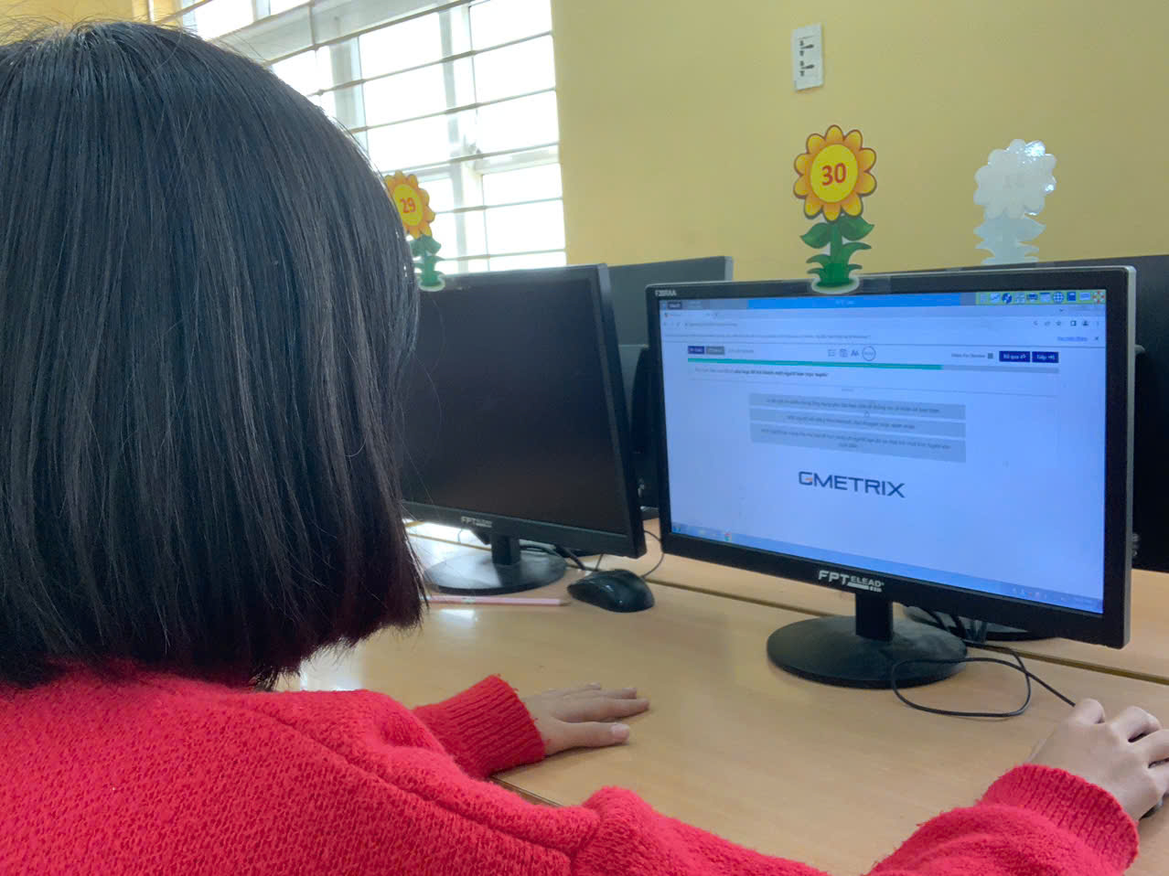 A person sitting at a desk with two computers

Description automatically generated