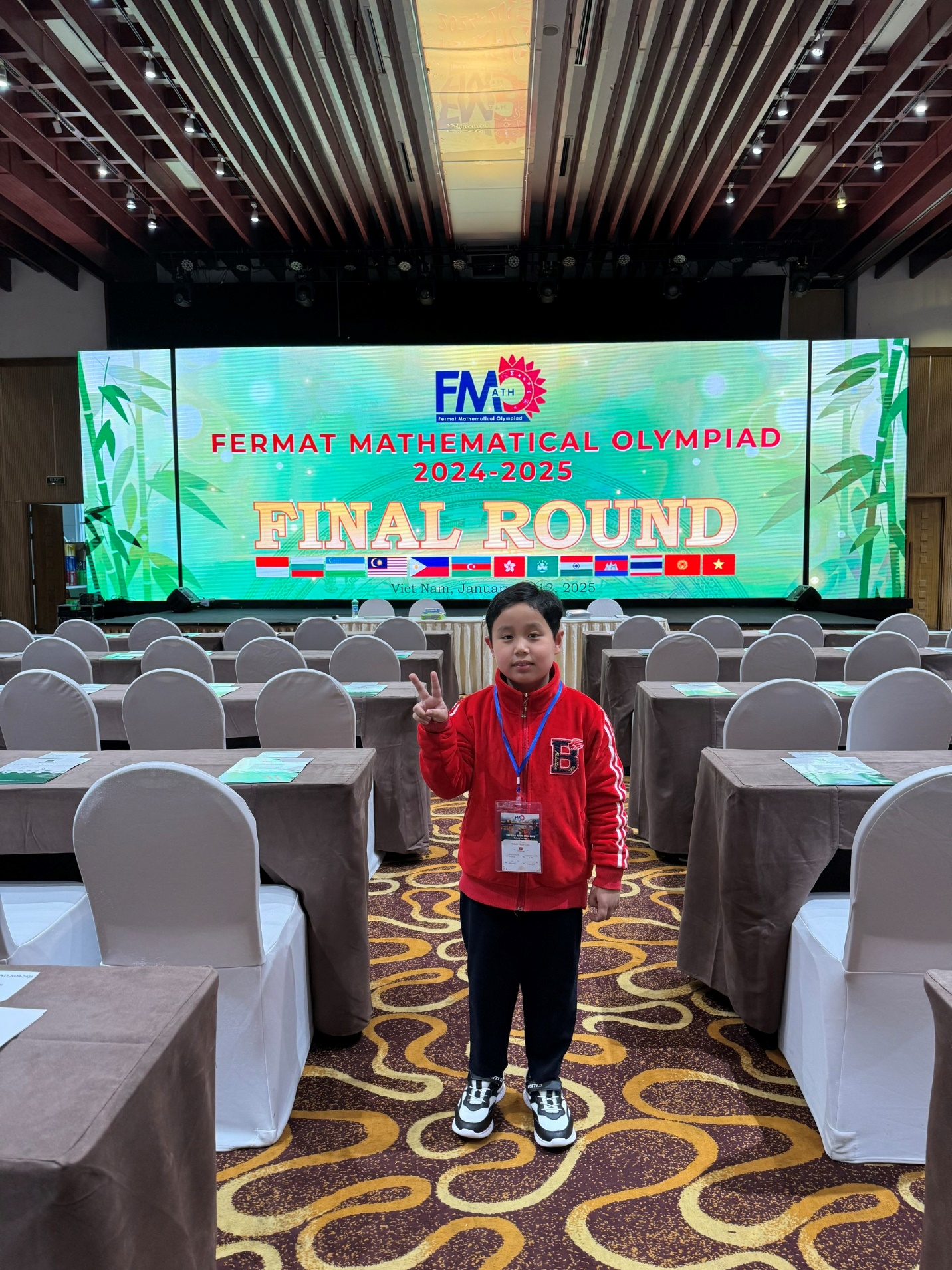 A child standing in a room with chairs and a large screen

Description automatically generated