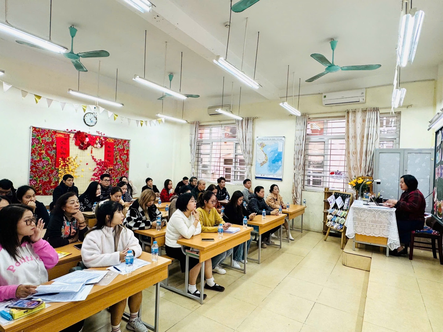 A group of people sitting at desks in a classroom

Description automatically generated