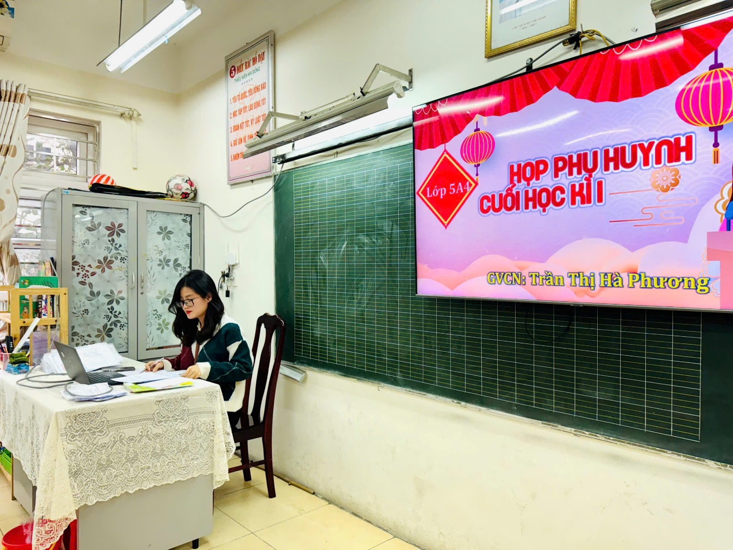 A person sitting at a desk in front of a chalkboard

Description automatically generated