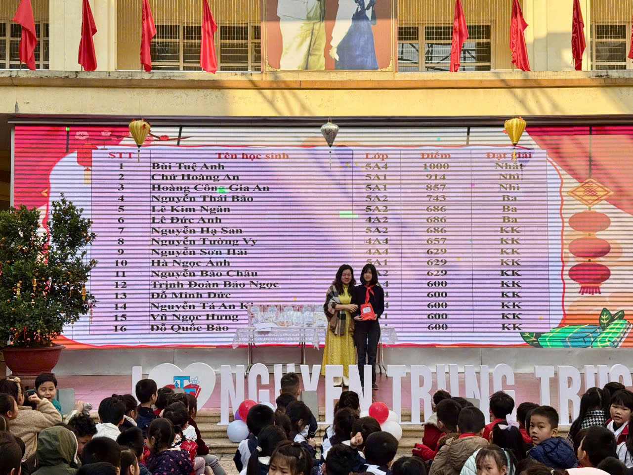 A group of people standing on steps in front of a large sign

Description automatically generated