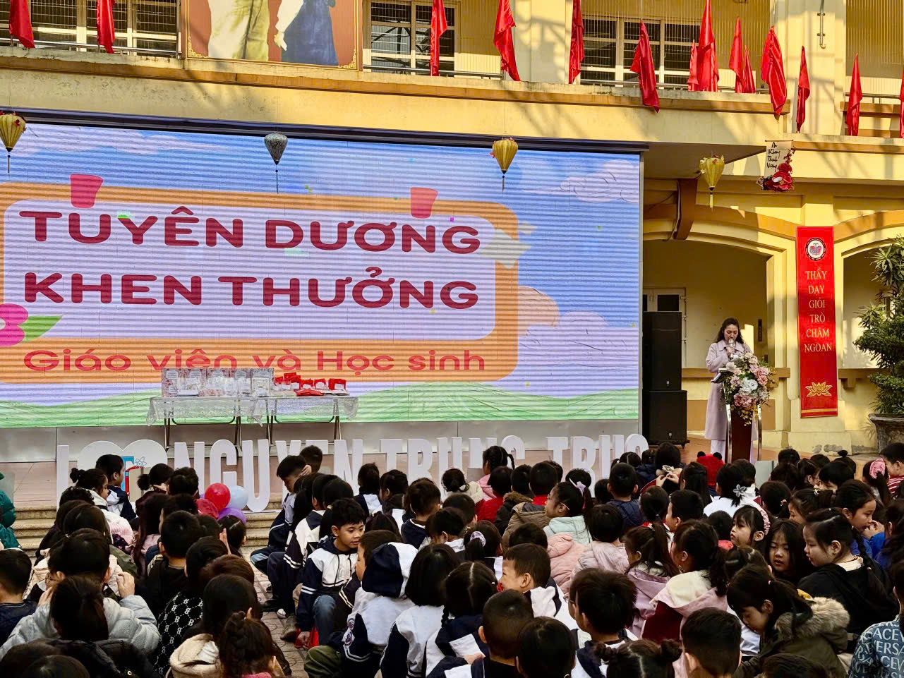 A group of children sitting in front of a stage

Description automatically generated