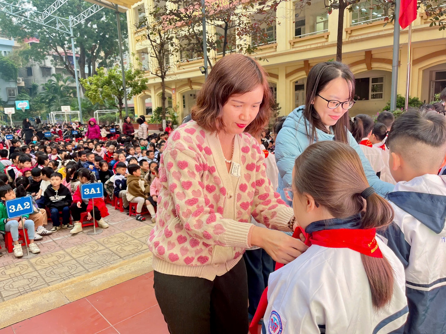 A person helping a child with a red scarf

Description automatically generated