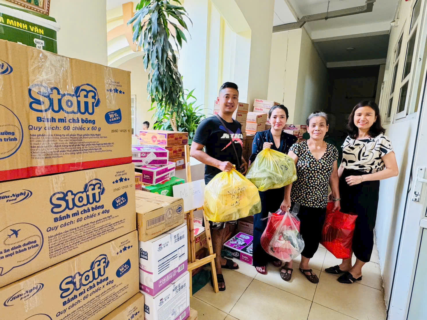 A group of people standing in a room with boxes and bags
AI-generated content may be incorrect.