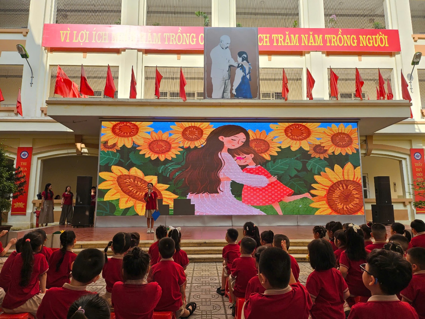 A group of children in red uniforms in front of a large screen
AI-generated content may be incorrect.