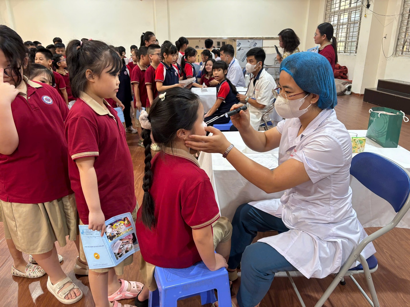 A person in a white coat and blue cap examining a child's face

AI-generated content may be incorrect.
