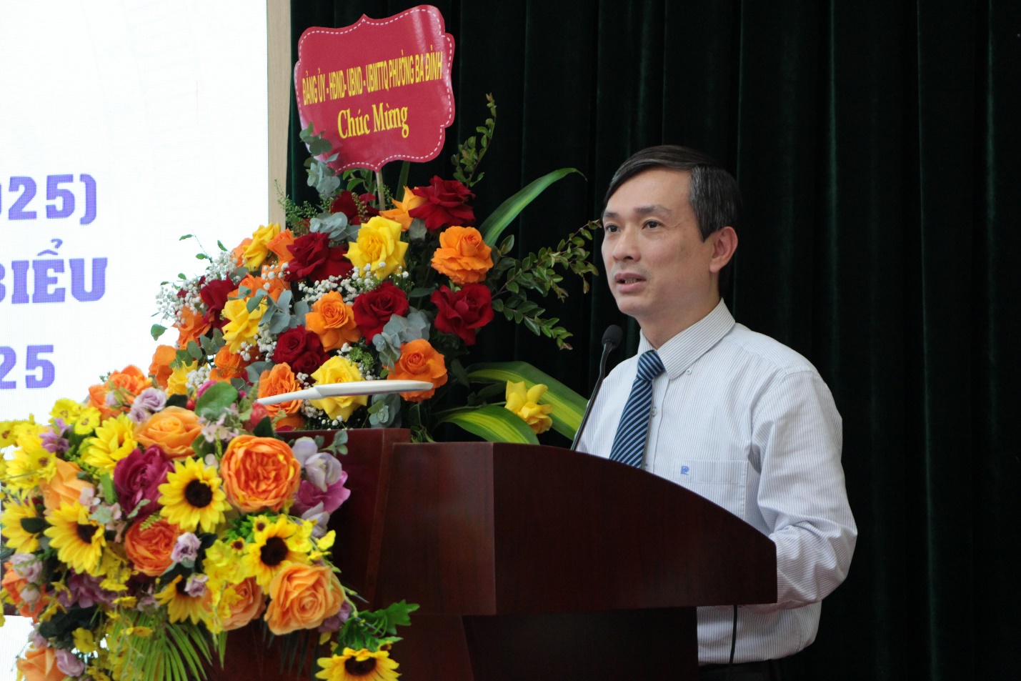 A person standing at a podium with flowers

AI-generated content may be incorrect.