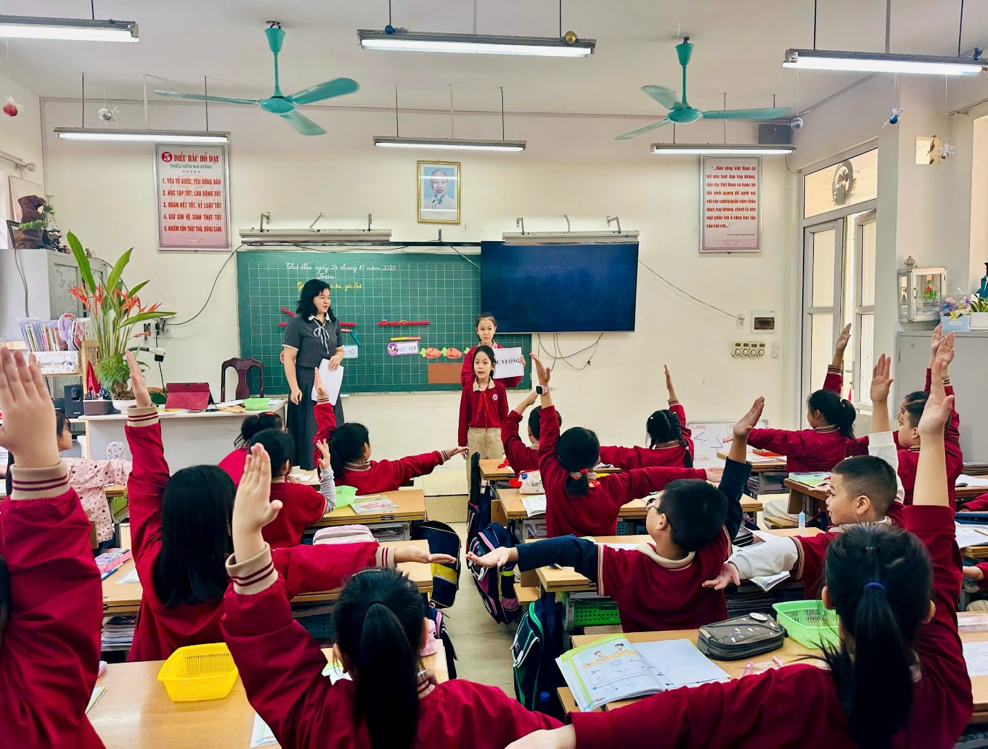 A group of students raising their hands in a classroom

AI-generated content may be incorrect.