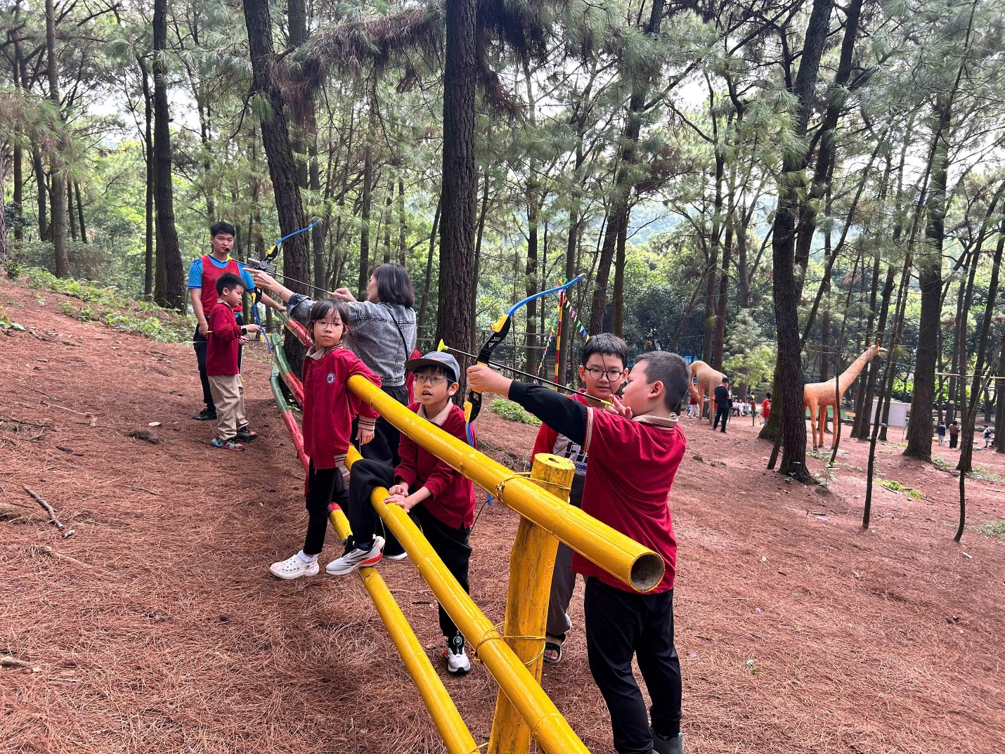 A group of kids in red shirts and red shirts standing on a yellow rail in a forest

AI-generated content may be incorrect.