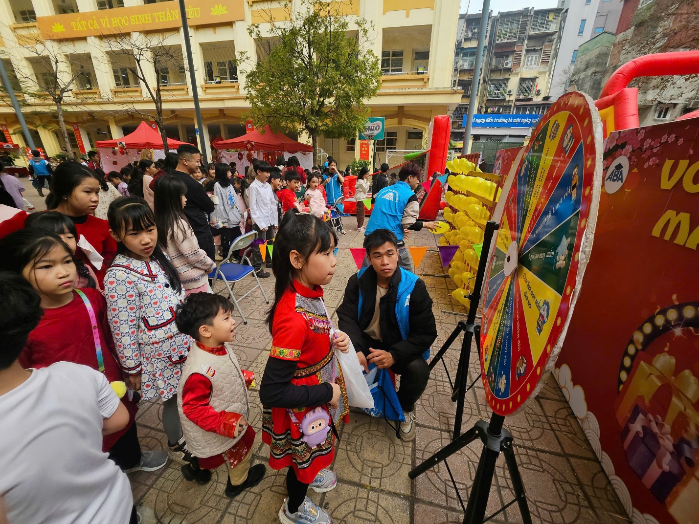 A group of kids standing in a street with a wheel of fortune

Description automatically generated