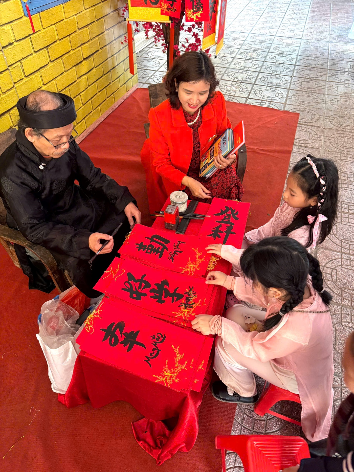A group of people sitting at a table with red paper

Description automatically generated