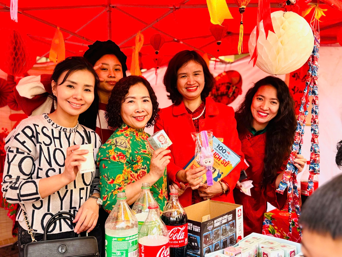 A group of women standing in front of a red tent

Description automatically generated
