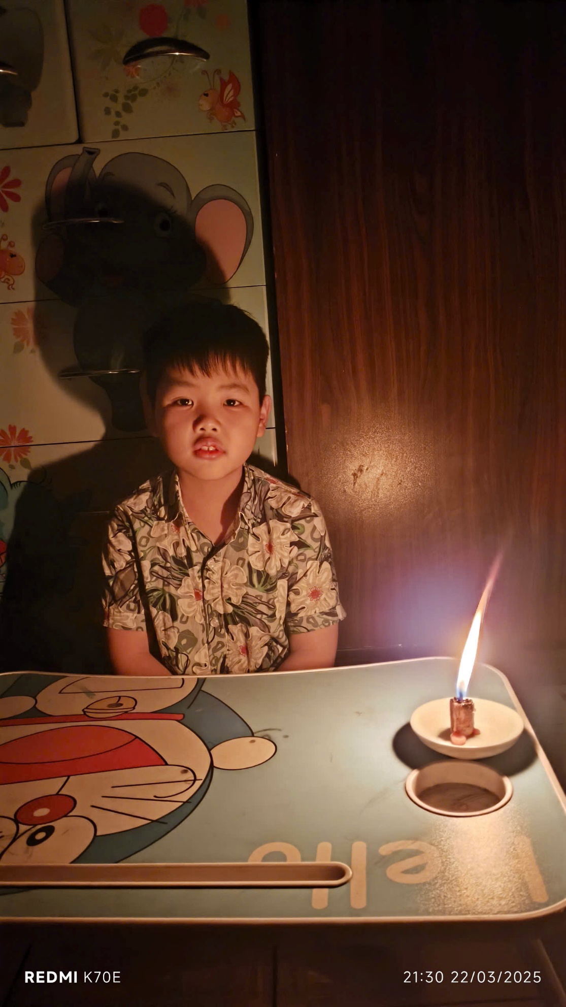 A child sitting at a table with a lit candle

AI-generated content may be incorrect.