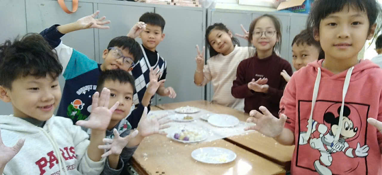A group of children sitting at a table with hands up
AI-generated content may be incorrect.