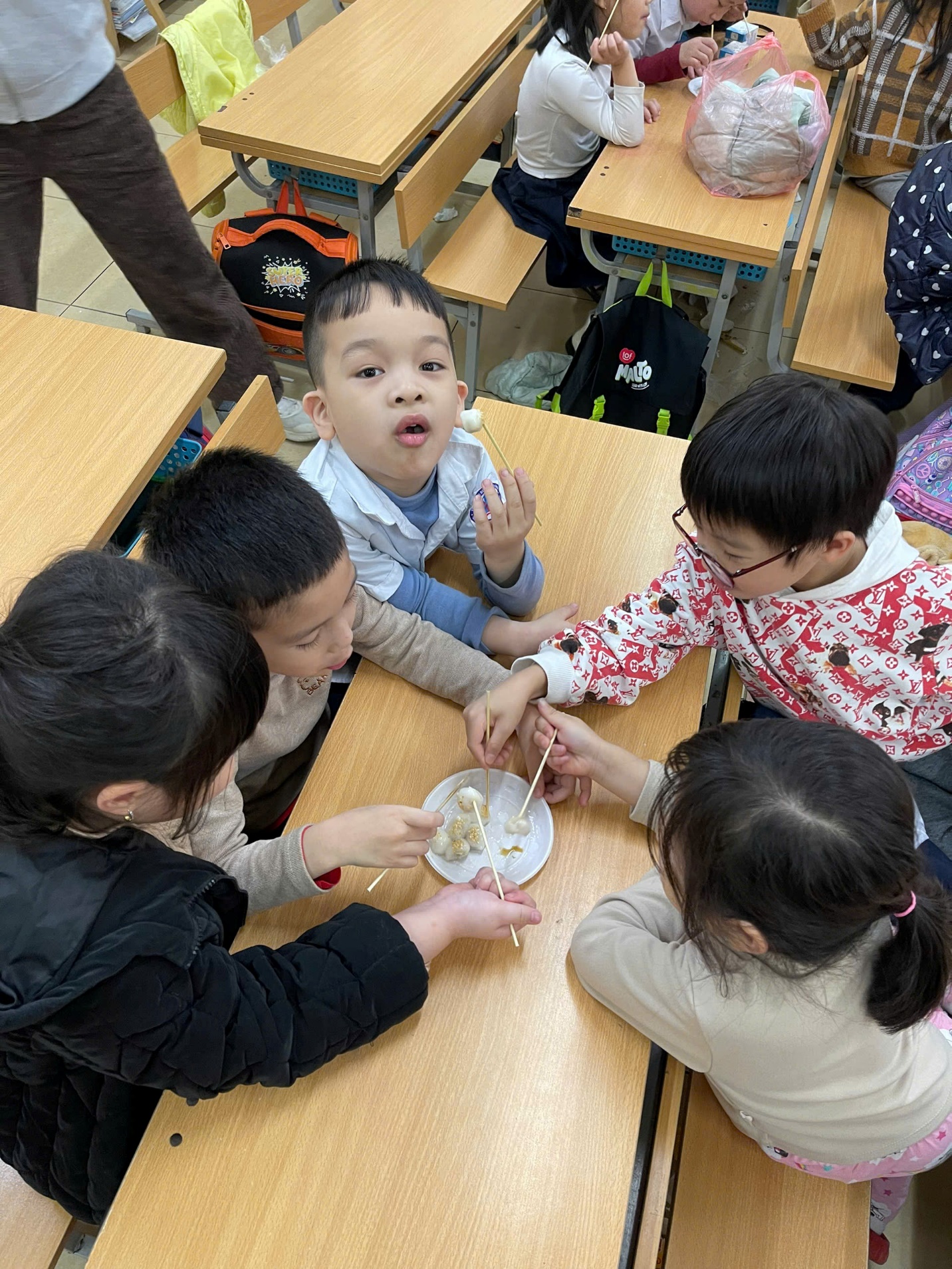 A group of children sitting at a table eating
AI-generated content may be incorrect.