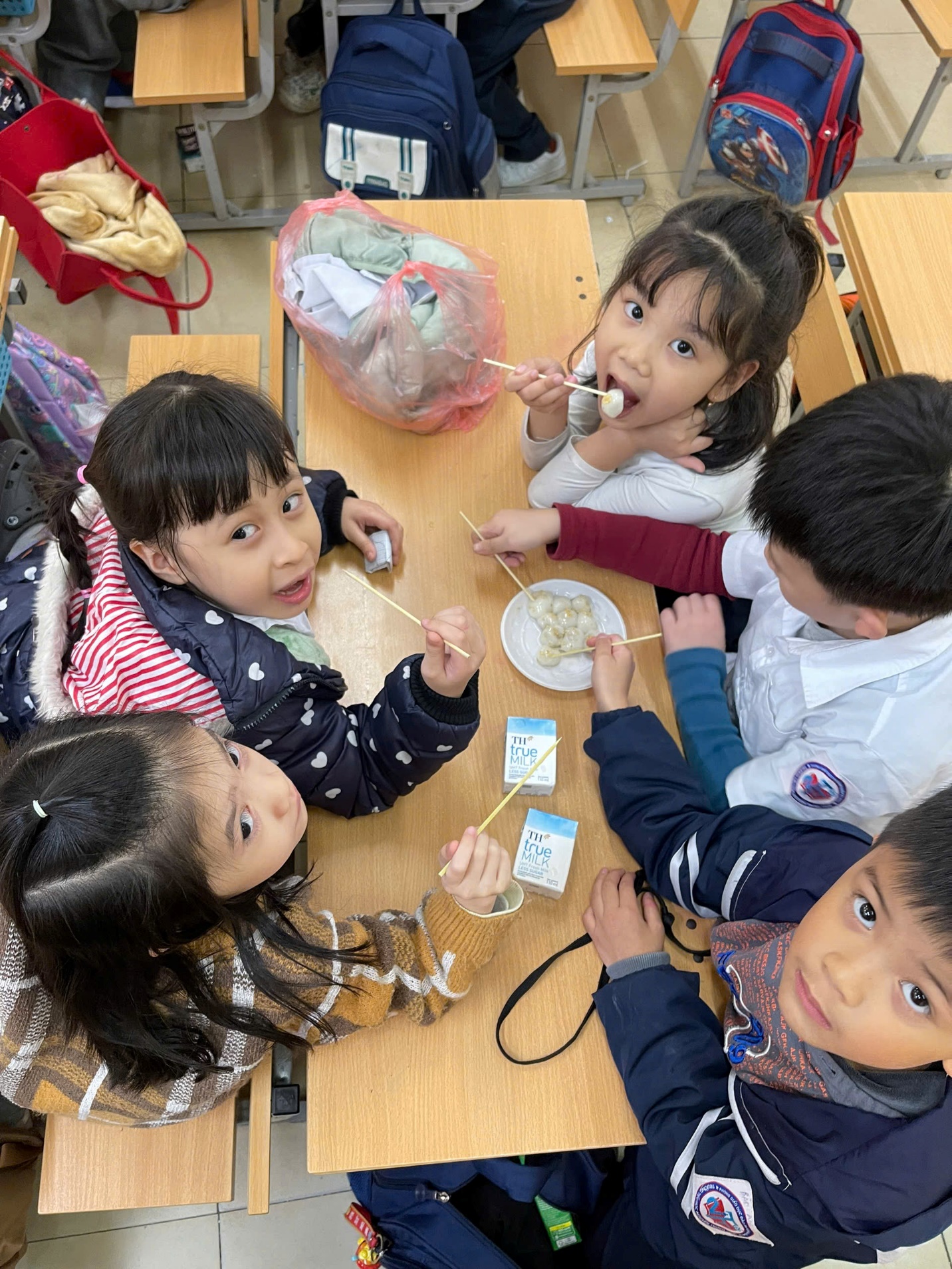 A group of children sitting at a table eating
AI-generated content may be incorrect.