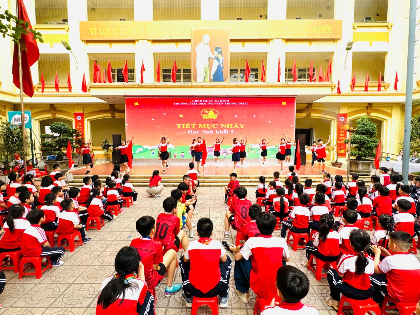 A group of children in red and white uniforms sitting on chairs

AI-generated content may be incorrect.