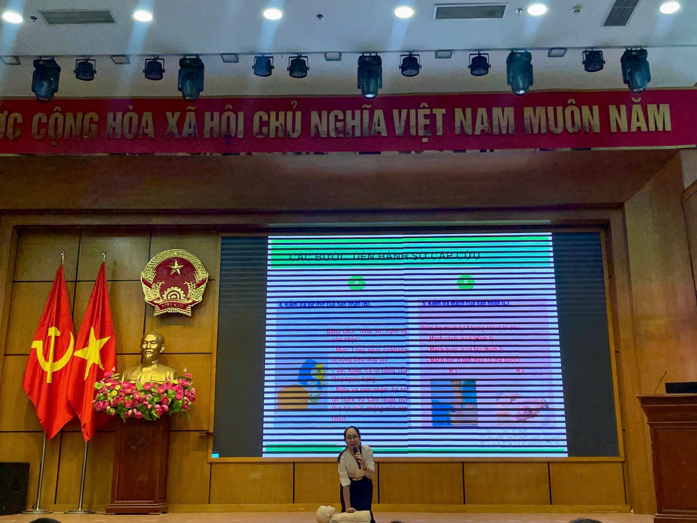 A person standing in front of a stage with a flag and a statue
AI-generated content may be incorrect.