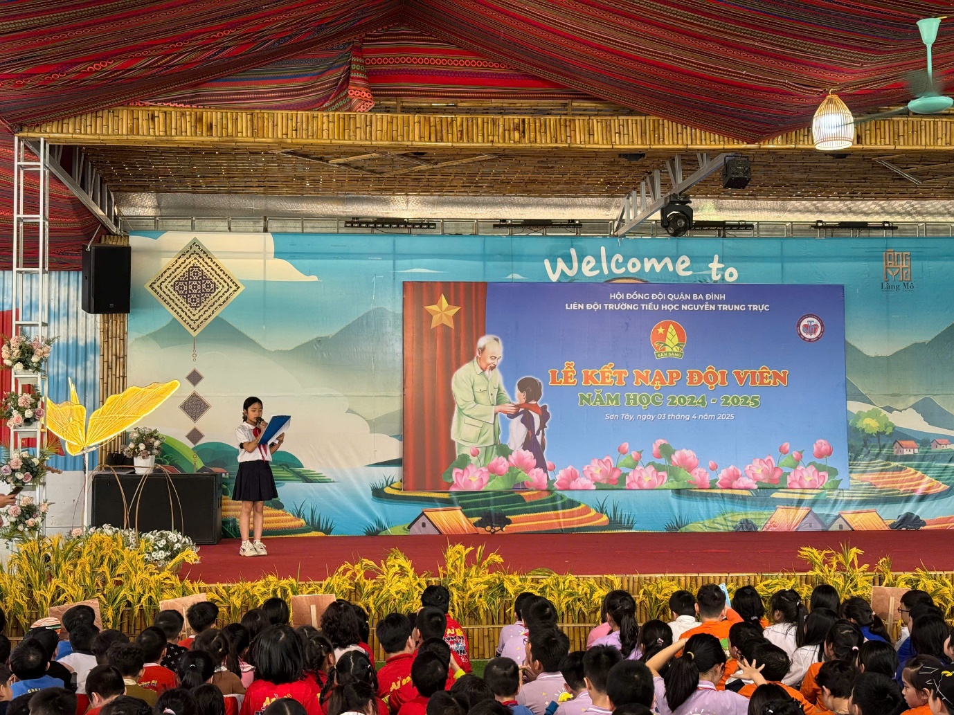 A child on a stage with a yellow umbrella and a large banner with people in the background
AI-generated content may be incorrect.