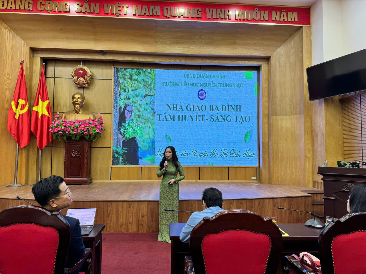 A person in a green dress standing in front of a screen
AI-generated content may be incorrect.